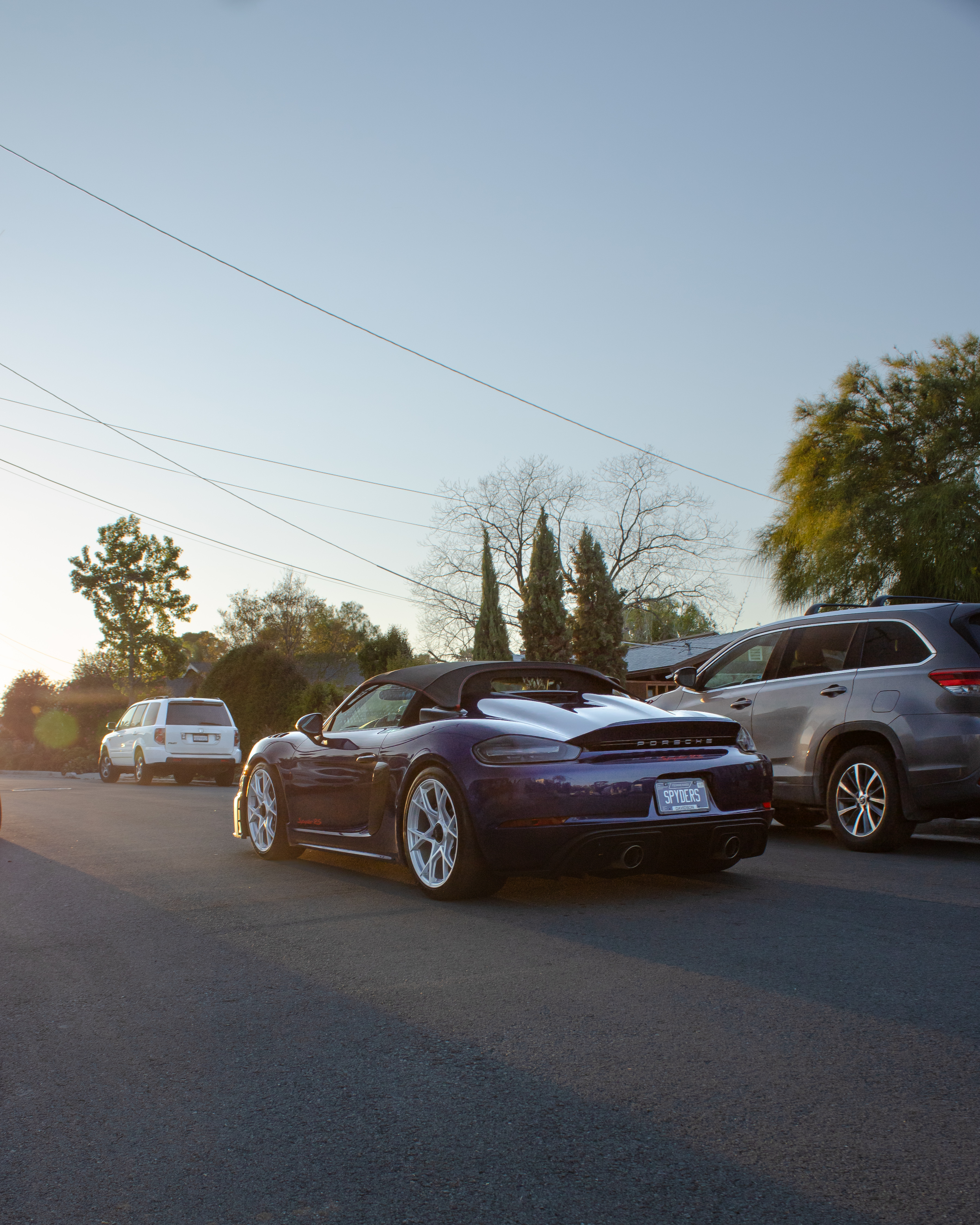 Rear of a blue Porsche 718 Spyder RS at golden hour